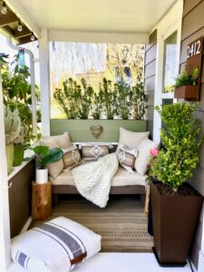 A small patio with compact seating, potted plants, and string lights above a tidy outdoor rug.