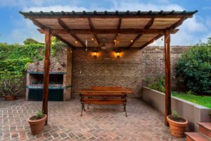 A family arranges solar lights along a backyard gravel pathway bordered by greenery and flower beds.