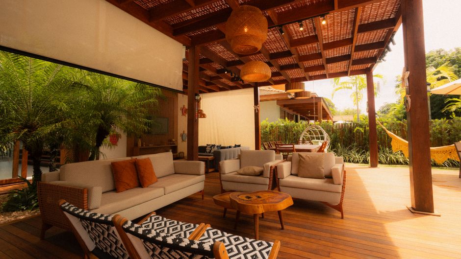 People relaxing on a shaded patio with fans and potted plants on a bright summer day